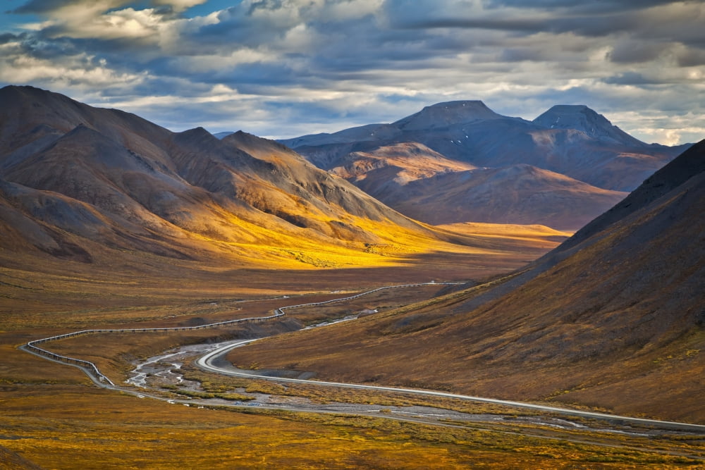 Sunset lighting Brooks Range at Chandalar Shelf viewed from Atigun Pass between Gates of the Arctic National Park & preserve and Arctic National Wildlife Refuge with Dalton Hwy and pipeline cutting th