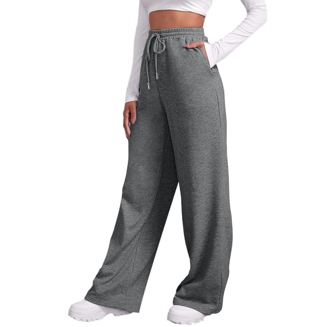 pantalones de chándal con forro polar para mujer: cintura alta, pierna recta ancha, bolsillos, poliéster, pantalones de chándal cálidos para otoño-invierno. Vista frontal centrada de pantalones grises de tiro alto con cintura elástica y cordón ajustable, pernera ancha y bolsillos laterales; tejido de punto de poliéster con forro polar visible, modelo con top corto blanco sobre fondo blanco. También adecuados como opción cómoda para viajes y descanso.