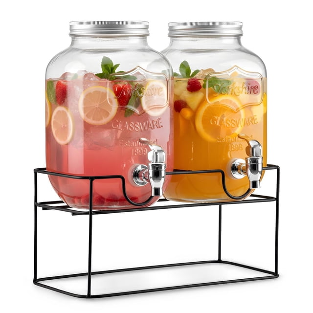 set de 2 dispensadores bebidas 4 litros mason jar con tapa y base metal kingshouse Multicolor — dos dispensadores de vidrio transparente de 4 L sobre base metálica negra; cada tarro con tapa metálica roscada y grifo cromado de flujo amplio; izquierdo con bebida rosada, rodajas de limón, fresas y hielo; derecho con bebida naranja, rodajas de naranja y hojas; incluye pizarrones y base. Ideal para servir limonadas y té en reuniones; también suele usarse para preparar y refrigerar bebidas caseras.