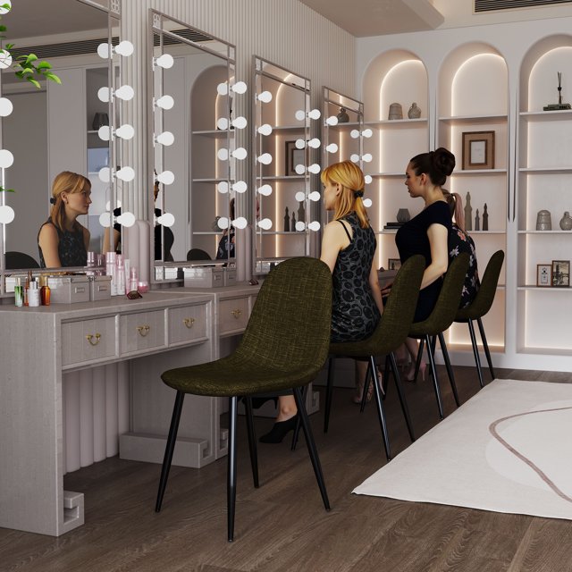 Four green fabric armless upholstered side chairs with black metal legs placed at a light gray vanity table featuring illuminated mirrors and decorative shelves.