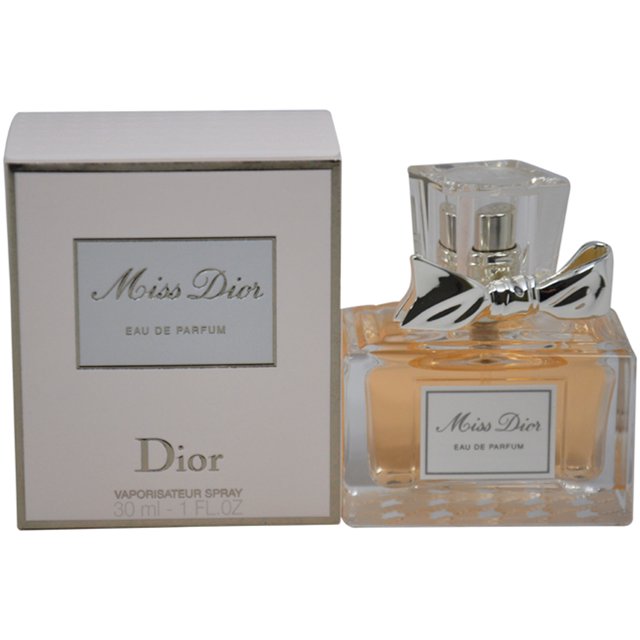 christian dior perfume spray edp 1 oz Christian Dior Miss Dior 1 oz spray; frontal view of clear rectangular glass bottle with pale amber liquid, faceted square cap and silver bow accent on the neck, shown beside pale pink boxed packaging labeled 'Miss Dior' and 'Dior'; fragancia femenina recomendada para la noche con notas de rosa, pachulí, violeta, mandarina, almizcle y jazmín.