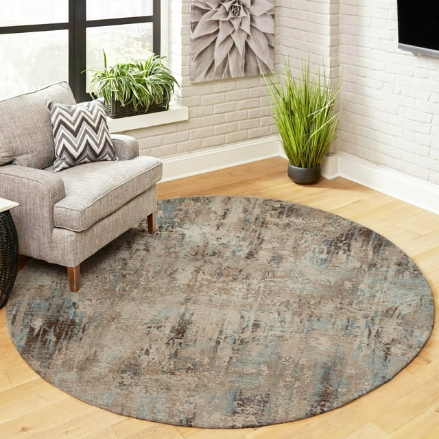 Round ECARPET Malia traditional area rug with muted blue and brown abstract patterns placed on hardwood floor in a modern living room corner.