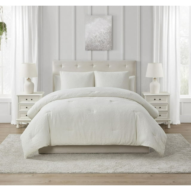 Springmaid Ensemble de Douillette Rowan à Médaillon en Blanc sur Lit Rembourré beige avec Tête de Lit Capitonnée, avec Motif de Médaillon Matelassé et Taies d'Oreiller Assorties. Cet Ensemble de Douillette Lavable à la Machine Ajoute une Touche Douillette et Propre à la Déco de Chambre, Montré avec des Tables de Nuit Blanches et des Lampes dans une Pièce Lumineuse avec des Murs à Panneaux Blancs et des Rideaux Transparents.