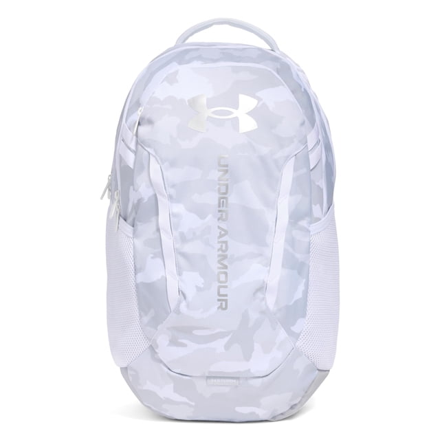 mochila under armour hustle 6.0 mod gris/plateado metalizado vista frontal centrada de mochila gris con patrón camuflaje claro y logo Under Armour plateado, compartimento principal con cierre, panel frontal con cremallera, bolsillos laterales de malla y asa superior; adecuada para organización diaria y uso en oficina.