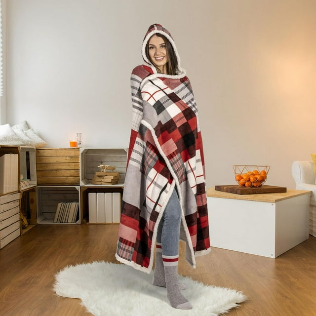 Plaid flannel hooded throw blanket with sherpa lining worn by person standing on white rug in modern living room.