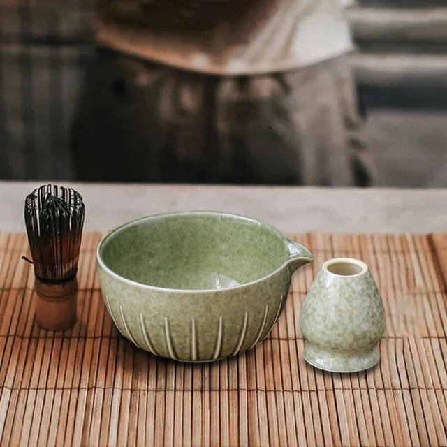 Japanese Matcha Bowl and Whisk Holder Gift Tea Accessories for Matcha Powder Green. This set includes a glazed ceramic matcha bowl measuring 14.5cm x 7.5cm (5.71in x 2.95in) and a whisk holder measuring 5.5cm x 6.3cm (2.17in x 2.48in). The bowl features a traditional Japanese-inspired green glaze design, perfect for preparing and serving matcha. Both items are displayed on a bamboo mat, highlighting their cultural authenticity and elegance.