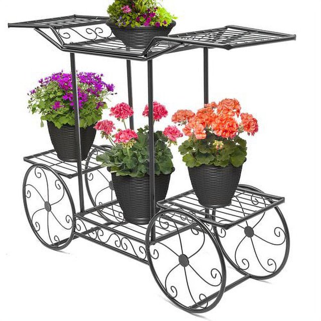 Sorbus Cart Stand 6 Flower Pot Display Rack in black, featuring a Parisian-style design with decorative scrollwork and non-rolling wheels. This metal plant stand has six tiers, three on the upper level and three on the lower level, for displaying potted plants, flowers, or garden decorations. Suitable for indoor and outdoor use, it measures approximately 31 inches long, 10 inches wide, and 25.62 inches high. Plants are not included.
