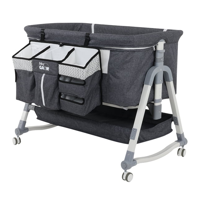 cuna colecho para bebe tipo corral con mecedora 5 niveles de altura ajustables cuna colecho Baby Gaon color Oxford en vista frontal 3/4; estructura metálica gris con patas en arco y ruedas, tejido textil gris oscuro, panel lateral con mosquitero, cambiador integrado y organizador colgante con bolsillos blancos y estampado geométrico; base tipo corral con bandeja inferior y columna ajustable de alturas visible. Suele usarse también como área de juego supervisada.