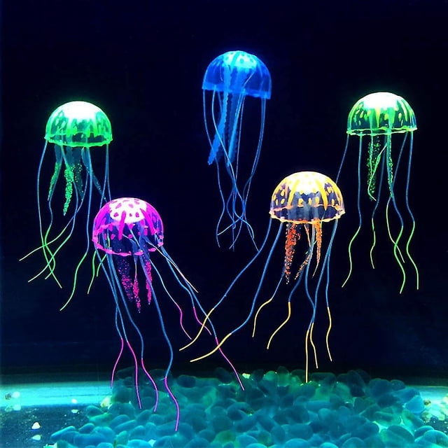 decoración de acuario medusas artificiales, 6 piezas — seis medusas artificiales de silicona en rosa, azul, verde, naranja, púrpura y amarillo, vista frontal flotando en un acuario con iluminación actínica; campanas translúcidas y tentáculos texturizados que imitan movimiento sobre grava oscura. También suelen usarse para decorar pequeños terrarios o escenas acuáticas decorativas.