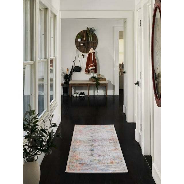 ECARPET Ethel traditional runner rug featuring a faded multicolor design placed on dark hardwood flooring in a bright hallway with white walls, near an upholstered bench and decorative wall shelf.