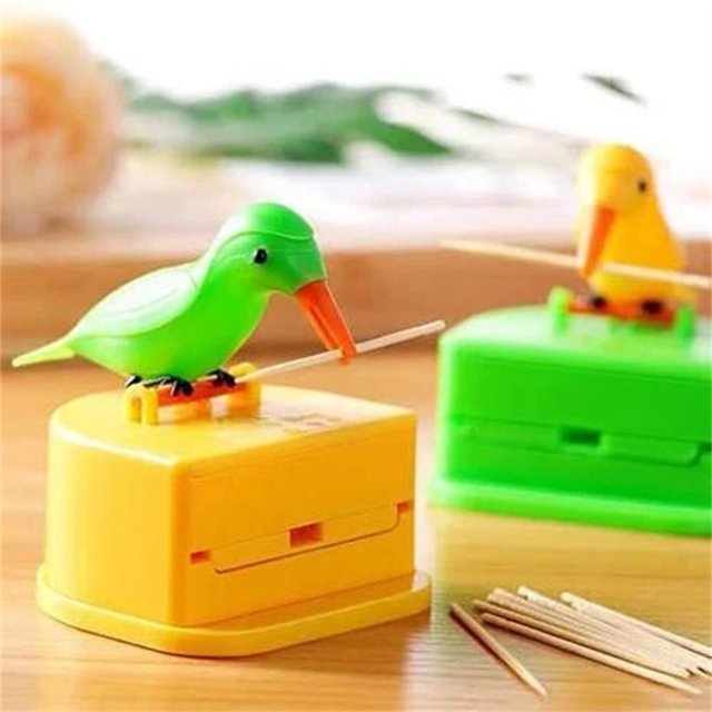 fiudx palillero para pájaros verde con diseño de presionar para expulsar, vista frontal centrada de pájaro de ABS con pico naranja sosteniendo un palillo sobre base cuadrada amarilla, ranura de expulsión visible y acabado liso; accesorio compacto ideal para reuniones familiares y como adorno para jaulas para pájaros.