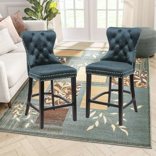 Set of two Ley black velvet counter stools with tufted backs, nailhead trim, and dark wood legs displayed in a modern living space.