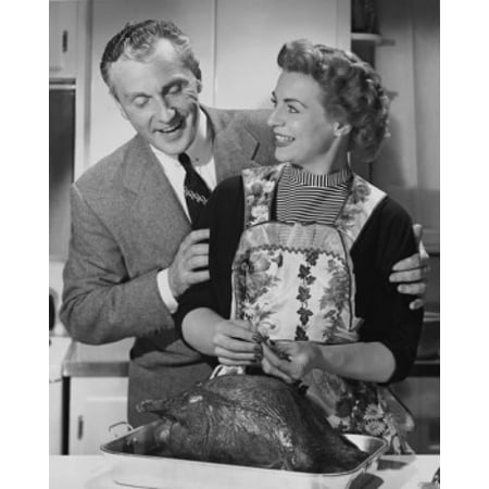Mid adult man woman preparing a turkey and a mid adult man holding her from behind Canvas Art -  (18 x 24)