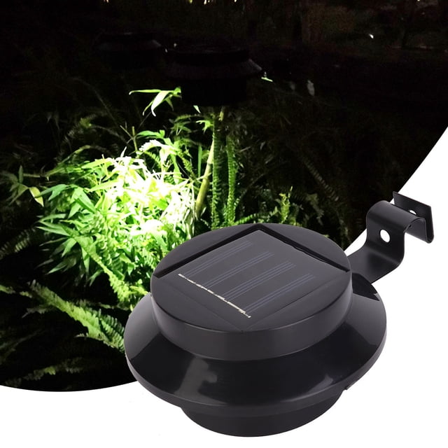 luz solar, lámpara solar exterior para valla de paisaje, luz de jardín, características de vanguardia lámpara solar de valla con panel solar superior, cuerpo ABS negro circular y 3 LED integrados, soporte en L para fijar a baranda o poste, tamaño aprox. 12 cm (4.7 in) y peso aprox. 143 g, vista en primer plano sobre jardín iluminado; a menudo se usa también para marcar senderos y escalones exteriores.