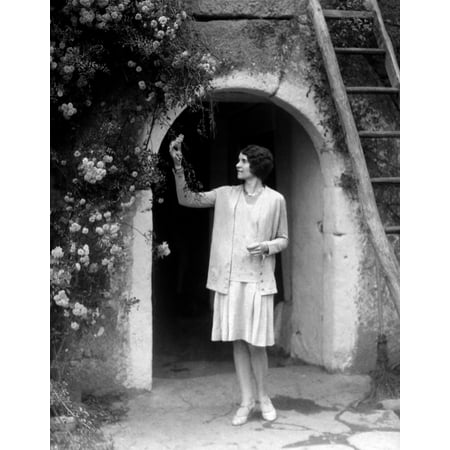 1920s-1930s Woman In Flapper Outfit Standing In Front Of Whitewashed Archway With Flowers Picking Bud Brittany France