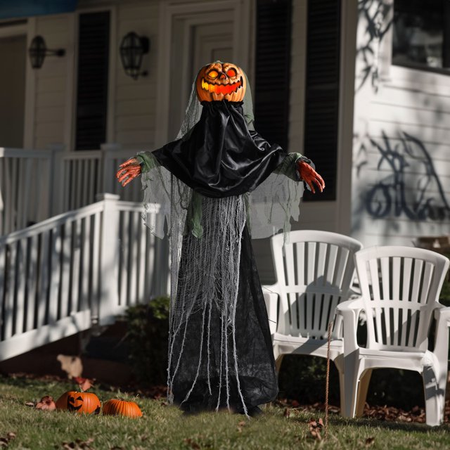 yescom scary animated halloween pumpkin decorations 5.4ft with motion & sound activated glowing head 2024 centered front-facing view of a 5.4 ft (164 cm) animatronic pumpkin ghost with a glowing carved jack-o'-lantern head, black polyester drape and tattered gray gauze overlay, outstretched orange ghost-like hands, flashing red lights in the head, freestanding on a four-leg base on a sunlit front porch lawn with white plastic chairs behind; battery-powered, sound-and-touch activated with three-mode control and tool-free assembly, suitable for porch or party décor and often used to create a spooky entryway display.