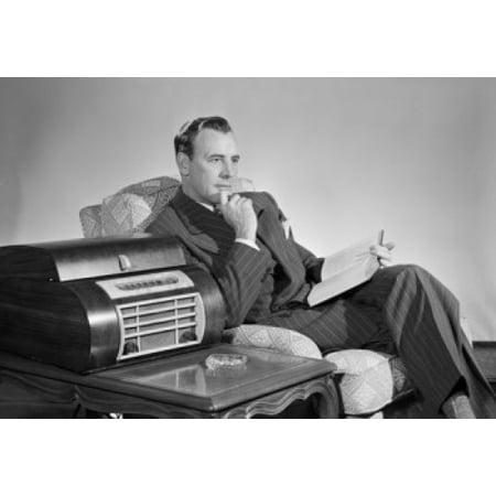 Mid adult man sitting in an armchair and listening to music Canvas Art - (24 x 36)