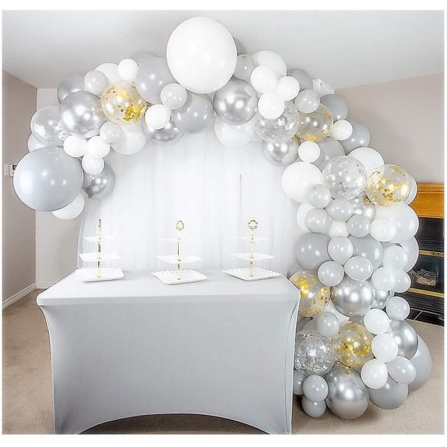 paquete de 155 kit de guirnalda y arco de globos blanco, plateado, dorado y gris de primera calidad con globos metálicos plateados y confeti, vista 3/4 de un arco curvo sobre mesa de buffet; globos de látex en blanco, gris, plata metálica y dorado en varios tamaños, globos transparentes con confeti dorado visibles, diseño interior con cortina blanca, guirnalda que puede alcanzar hasta 16 pies.