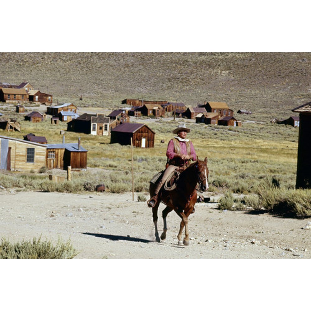John Wayne riding through western town on horseback classic image 24x36