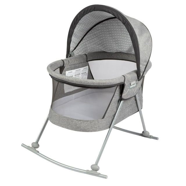 cuna moisés mecedor safety 1st nap & go bt080g cuna-moisés gris 2-en-1 en modo fijo o mecedora, vista frontal 3/4 con capota semiabierta; estructura metálica plateada, laterales de malla para ventilación y visibilidad, colchón acolchado y telas suaves gris jaspeado, mosquitero removible y plegado compacto para bolsa de viaje; uso desde recién nacido hasta 9 kg; a menudo se usa también como espacio portátil para siestas en casa o viajes cortos.
