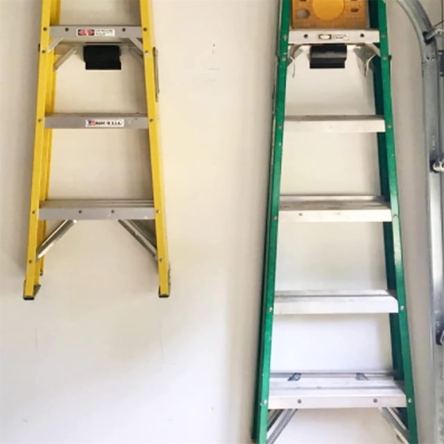 Metal Ladder Organizer, Wall Mount Ladder Grabber installed on a garage wall holding two extension ladders, one yellow and one green. This heavy-duty wall mount, made of powder-coated steel, supports up to 50 lbs and is suitable for indoor and outdoor use. Includes mounting screws and expansion tubes for easy installation on brick, wood, or other wall surfaces. Ideal for garage storage and space-saving organization.