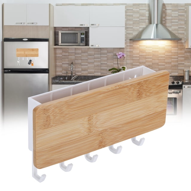 Wall Organizer Key Holder, a wall-mounted key holder made of bamboo and ABS material, featuring a wood-colored storage box with five white hooks for hanging keys. Compact size of approximately 18.5 x 10 x 3.5 cm (7.3 x 3.9 x 1.4 in) and lightweight at 122 g (4.3 oz). Shown in a modern kitchen setting, mounted on a refrigerator. Includes nails and double-sided adhesive tape for versatile installation.