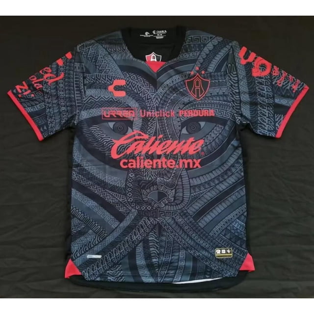 camiseta atlas f.c . edición especial negra 22/23pangjing playera negra 22/23 con patrón tribal azul oscuro que forma un rostro estilizado en el frente; cuello en V negro, escudo del club en pecho izquierdo, patrocinador "caliente" en rojo al centro, mangas cortas con ribete rojo, tejido 100% poliéster. Personalizable con nombre y número según notas del vendedor.