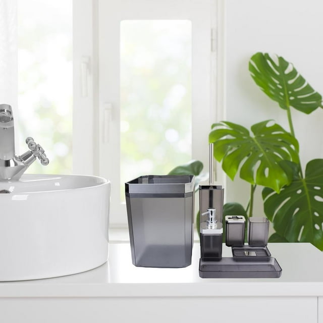 suministros de baño macarena juego de accesorios 7 piezas gris conjunto frontal sobre encimera blanca con dispensador de loción, jabonera, vaso para enjuague, soporte para cepillo dental, bandeja, bote de basura y escobilla con soporte en plástico PP gris; diseño moderno junto a lavabo, adecuado para hogares y hoteles y también usado como organizador de tocador.