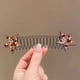 thumbnail image 1 of La parte posterior de la cabeza se fija con una horquilla invisible y una pinza elástica para el cabello con forma de estrella de colores., 1 of 3
