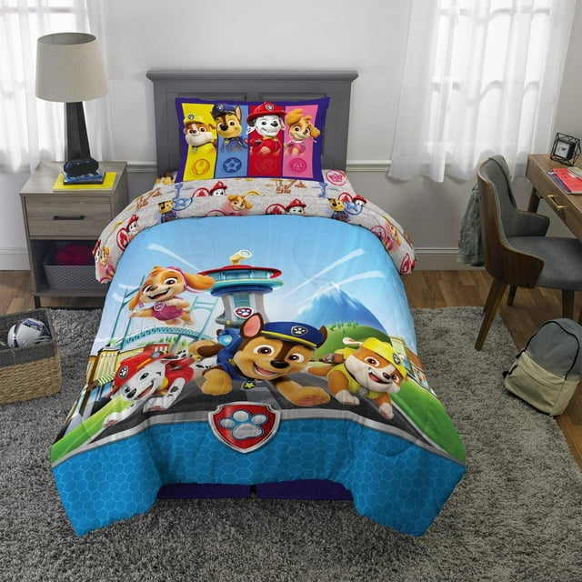 Paw Patrol 'Barking Buds' twin full comforter and pillowcase set with colorful animated pups Chase, Marshall, Skye, Rubble on blue background in a kid's bedroom.