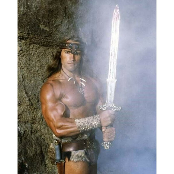 Arnold Schwarzenegger holds the gleaming sword as Conan The Barbarian poster