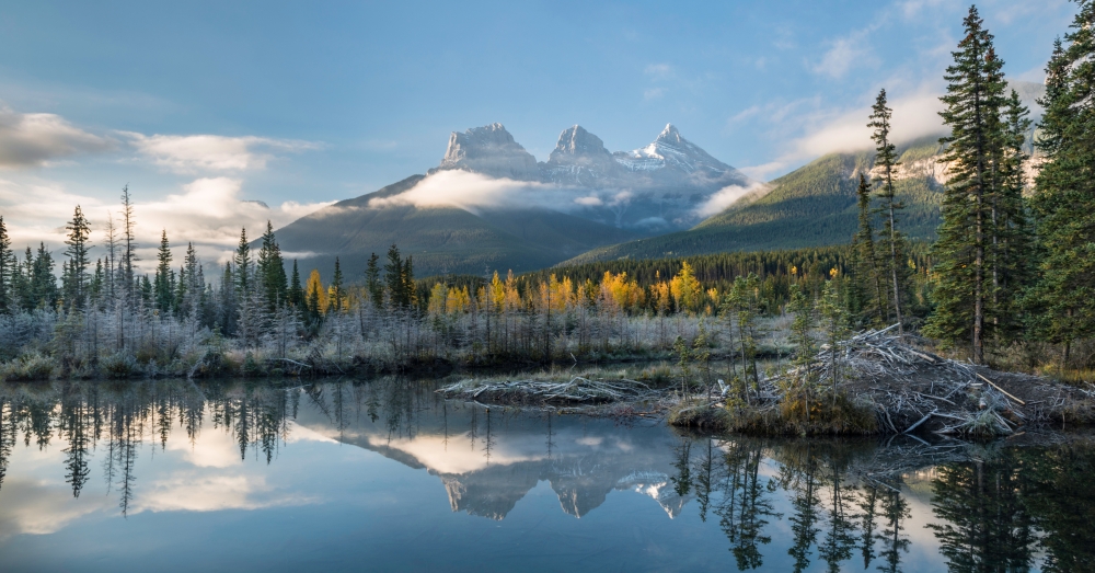 Lake with mountains in background, Beaverlodge, Three Sisters, Canmore, Alberta, Canada Poster