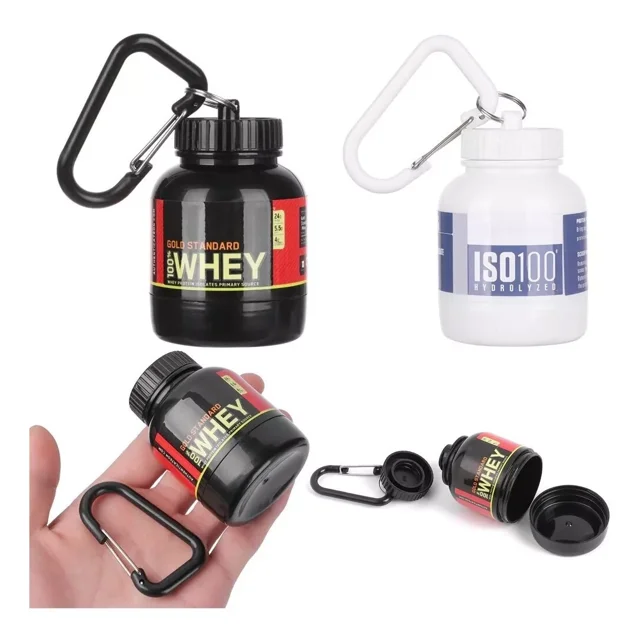 set 2 piezas embudo llavero porta proteína 30g contenedor — Dos contenedores plásticos rellenables con doble tapa rosca y mosquetón, estilo frasco de suplemento (7.5 x 5 cm), uno negro y uno blanco con calcomanía; se muestran cerrados, uno abierto con tapa separada y sostenido en mano para escala. Adecuado para llevar polvo de proteína en mochila o cangurera.