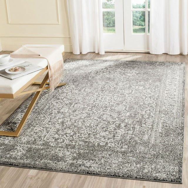 Safavieh Evoke Trena traditional area rug featuring a distressed gray and white intricate pattern, displayed on light wood flooring near glass doors.