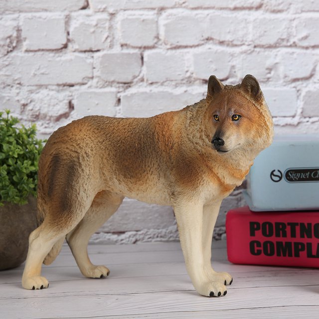 modelo de lobo marrón juguete, decoración de escrito toy educate modelo de lobo marrón, herramienta de enseñanza de modelo estereoscópico para bebé: vista lateral 3/4 de un modelo de lobo marrón de plástico (aprox. 17.8 x 7.8 x 12.8 cm) con textura de pelaje en tonos marrón y crema, ojos amarillos pintados y hocico oscuro; patas en posición de pie frente a pared de ladrillo blanco y libros apilados. Idóneo como apoyo didáctico y decoración en aulas o juegos educativos.