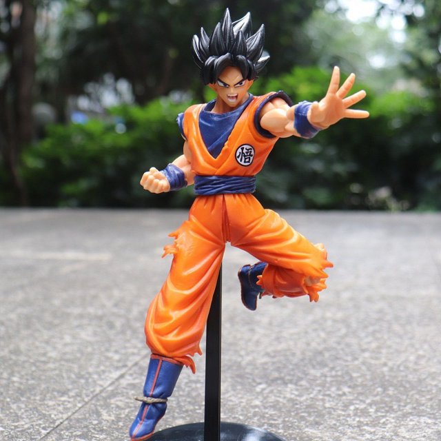 dragon ball super saiyan goku gohan goten vegeta trunks figura de anime modelo adornos Figura de Goku con traje naranja y cabello negro en puesto de pelea, apoyada en soporte vertical negro desde una base redonda; pintura PVC visible, pliegues rasgados en el gi y botas azules, fondo exterior desenfocado; a menudo se usa como adorno de estanterías o escritorios.