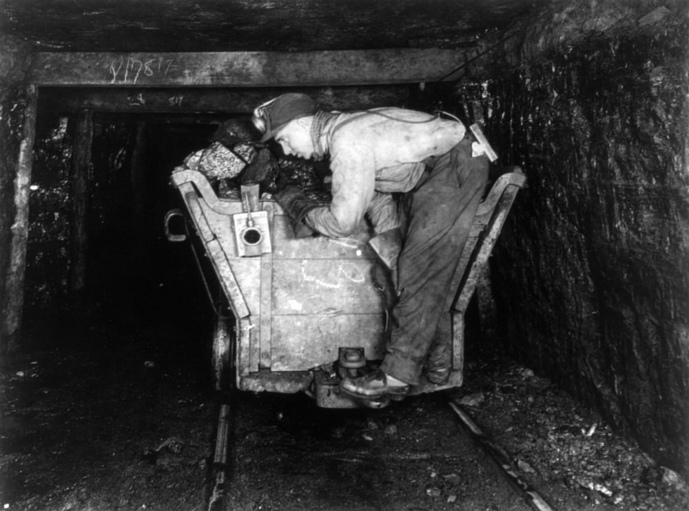 Coal Miner, C1915. /Na Coal Miner Standing On The Back Of Coal Mining
