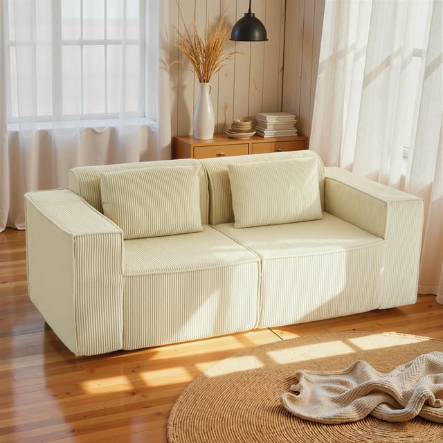 HOMCOM Boneless Couch, Corduroy 3 Seater Sofa with 2 Pillows, Beige, ideal for living room seating. The sofa features soft beige corduroy upholstery, wide armrests, and two matching pillows. Its spacious design includes thick foam padding for comfort and deep seating for relaxation. Positioned on a wooden floor with natural light streaming through sheer curtains.