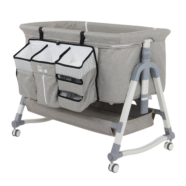 cuna colecho para bebe tipo corral con mecedora 5 niveles de altura ajustables baby gaon bczn02 cuna colecho gris, vista frontal 3/4; estructura plegable con patas gris claro y ruedas, laterales acolchados y mosquitero integrado, bolsillera organizadora frontal y cambiador incorporado, bandeja inferior para almacenamiento y mecanismo de mecedora visible; también se usa como corral y es adecuada para cambiar pañales de forma conveniente.