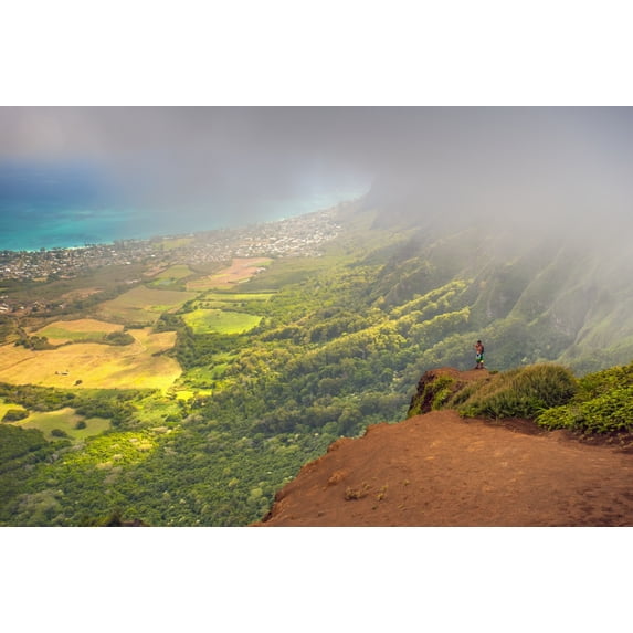Item # DPI12256302LARGE A man standing on the edge of a cliff on the Kuliouou Ridge Trial enjoys the view of Oahus windward side and the town of Waimanalo as the clouds roll in on a summers day Waiman