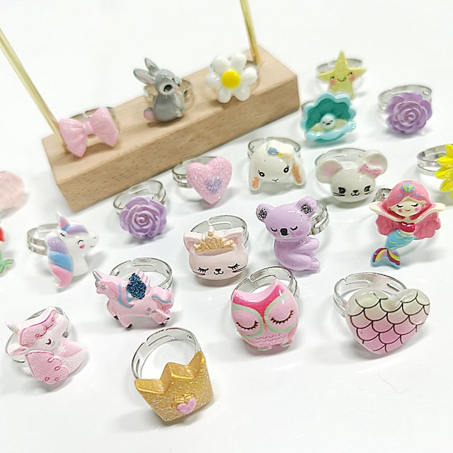 anillo de aleación ajustable con dibujos animados para niños de estilo transfronterizo, lindo anillo de sirena con unicornio para niña — Plano medio frontal con varios anillos infantiles ajustables sobre fondo blanco; motivos esmaltados visibles como sirena roja, unicornio rosa, búho y koala lila, corona dorada y escama de sirena; bordes metálicos plateados; diseño ajustable indicado para niños de 3 a 10 años; a menudo usados como accesorio de juego o detalle de disfraz.