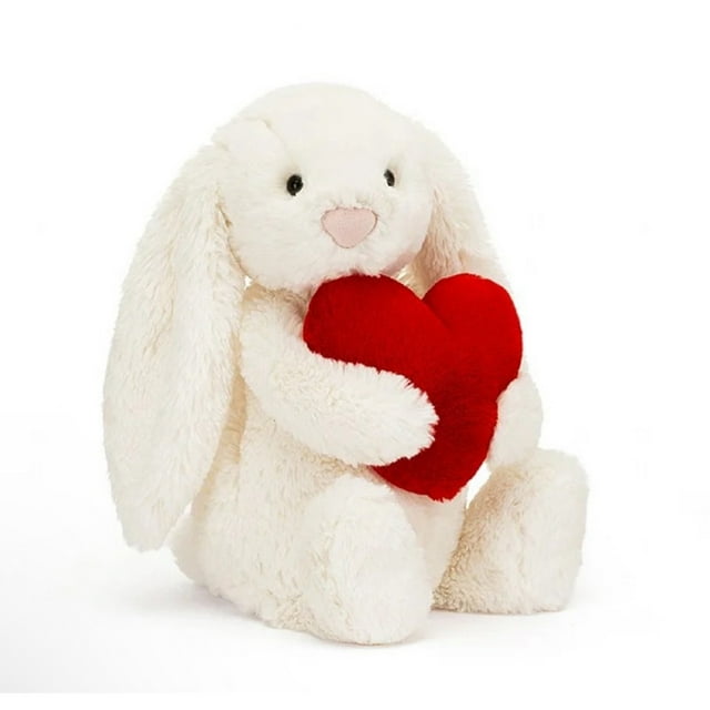 jellycat, jelly cat, jellycat stuffed animals, 11" tall jellycats plushies, all jellycat, jelly cats stuffed toys, jellycat plush toys gifts for girls boys kids children blanco conejito de peluche de 30 cm, vista frontal 3/4 sentado, orejas largas caídas, pelaje corto y suave, ojos y boca bordados, abraza un cojín rojo en forma de corazón; fondo blanco. A menudo usado como juguete de consuelo o decoración de cuarto infantil.
