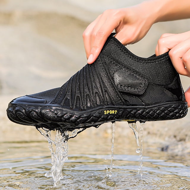 zapatos acuáticos aqua shoes zapatillas de buceo transpirables para caminar en el lago (negro 39) Primer plano 3/4 de una zapatilla acuática negra talla 39 sostenida con ambas manos; parte superior elástica KPU+malla con costuras visibles, suela de goma texturizada con orificios de drenaje y la marca 'SPORT', agua escurriendo por la suela. Adecuadas para senderismo en ríos y actividades acuáticas, también suelen usarse para caminar en la playa.