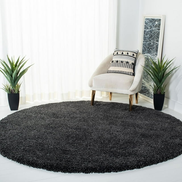 Round black Safavieh Milan Harlow solid shag area rug displayed under a beige accent chair with decorative pillow in a modern, light-filled room.