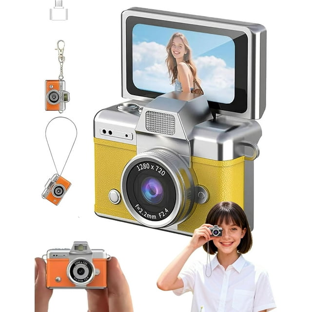 cámara de vlogs digital mini con pantalla abatible de 1.47" Vista 3/4 frontal de una mini cámara color amarillo con pantalla LCD abatible girada hacia atrás, lente con inscripción 1280 x 720 y anillo marcado f=2.2mm F2.4, flash integrado en la parte superior plateada, cuerpo compacto con textoural visible, accesorios incluidos mostrados: llavero, cordón y lector de tarjetas, y una persona sujetando la cámara para selfie; también es adecuada como cámara portátil para vlogs y selfies.