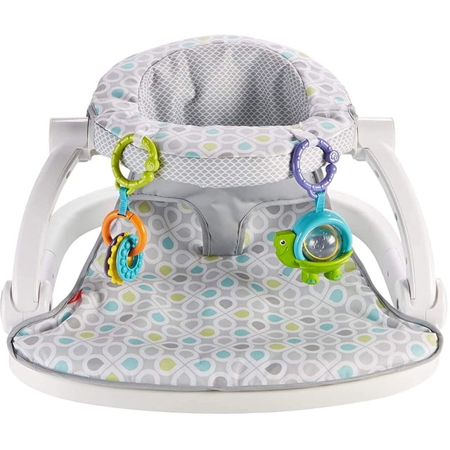 asiento de piso fisher-price sit-me-up fisher price fisher-price multicolor. Vista frontal centrada de asiento para bebés con base ancha y respaldo acolchado con malla, funda gris estampada con círculos azules y verdes, arnés integrado y barra frontal con juguetes colgantes (anillas y tortuga con espejo).