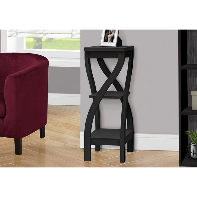 Black laminate Monarch Specialties accent table with curved X-shaped legs and two shelves, styled as side or plant stand in a transitional living room setting.