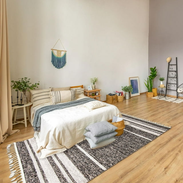 Southwestern Earth Collection rug featuring black, white, and beige stripes on a wooden floor in a bright bedroom setting.