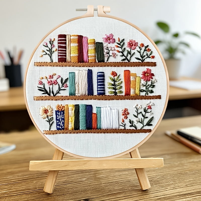 An Embroidery Kit Featuring a Bookshelf Floral Pattern Measuring, Suitable for Both Adults And Beginners. It Includes Instructions, Printed Fabric, an Embroidery Hoop, And Needle And Thread