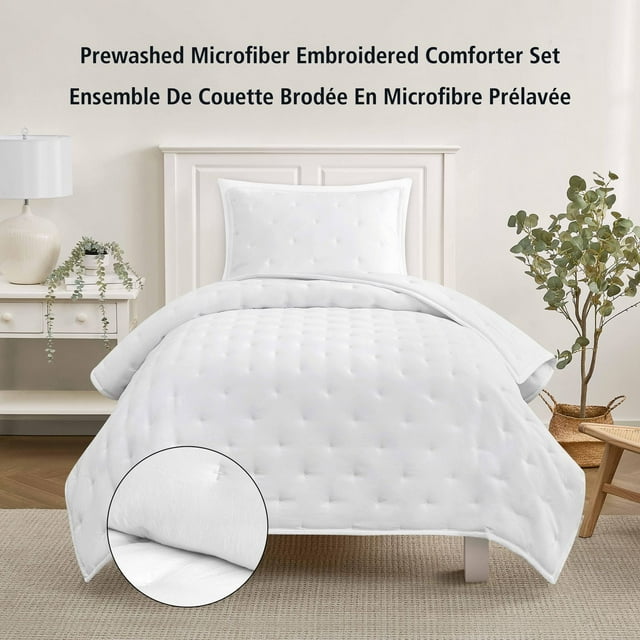 Twin Arctic White microfiber comforter and pillow sham set with embroidered tufted design displayed on bed in cozy room.